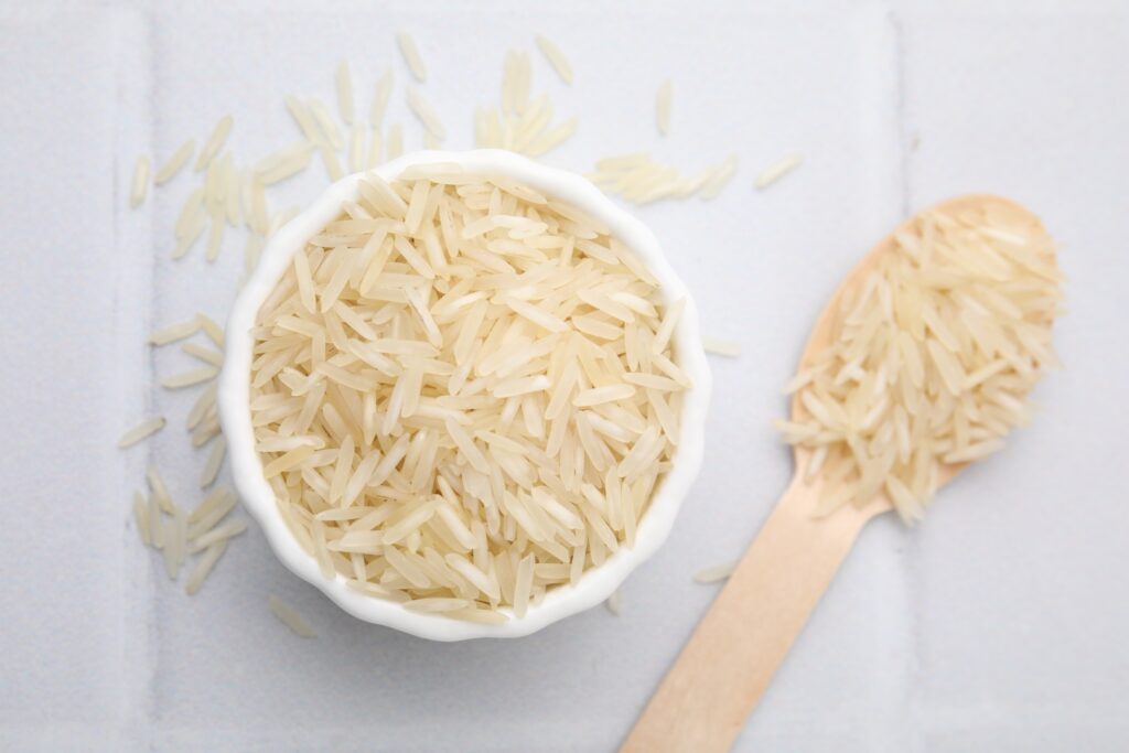 Bowl and spoon with raw rice on white tiled table. Credit- Shutterstock