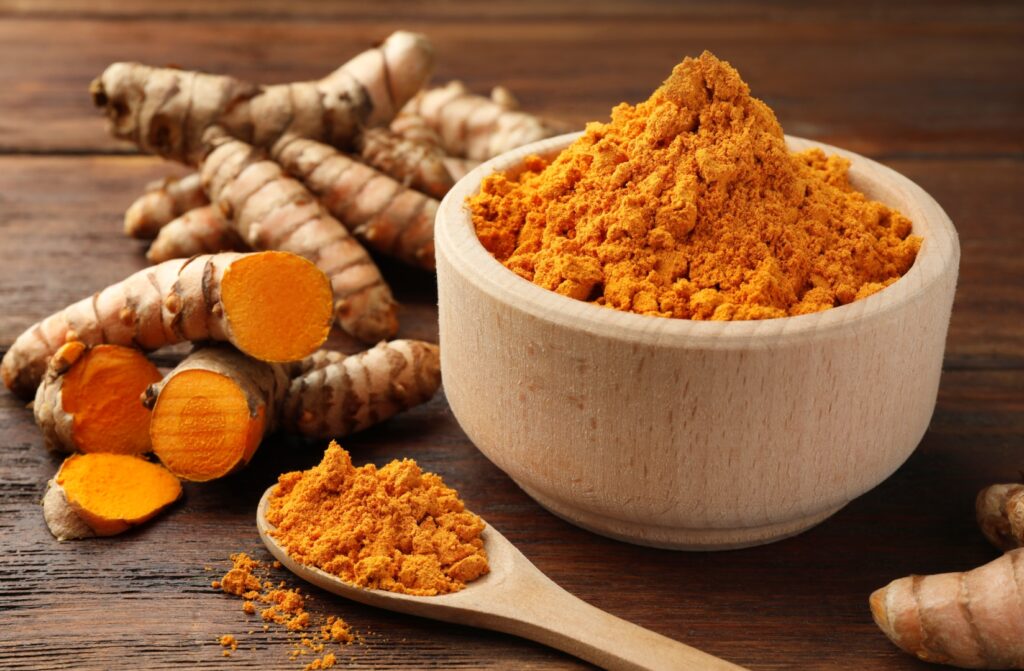 Aromatic turmeric powder and raw roots on wooden table Credit: shutterstock