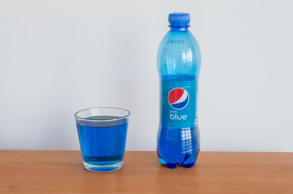 Una botella contemporánea al lado de un vaso de Pepsi Blue. Imagen a través de Shutterstock