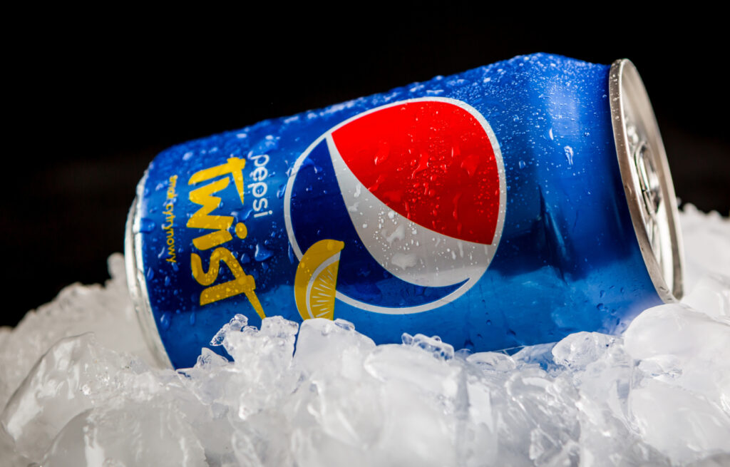 Lattina di Pepsi Twist spruzzata con acqua su cubetti di ghiaccio. Immagine tramite Shutterstock