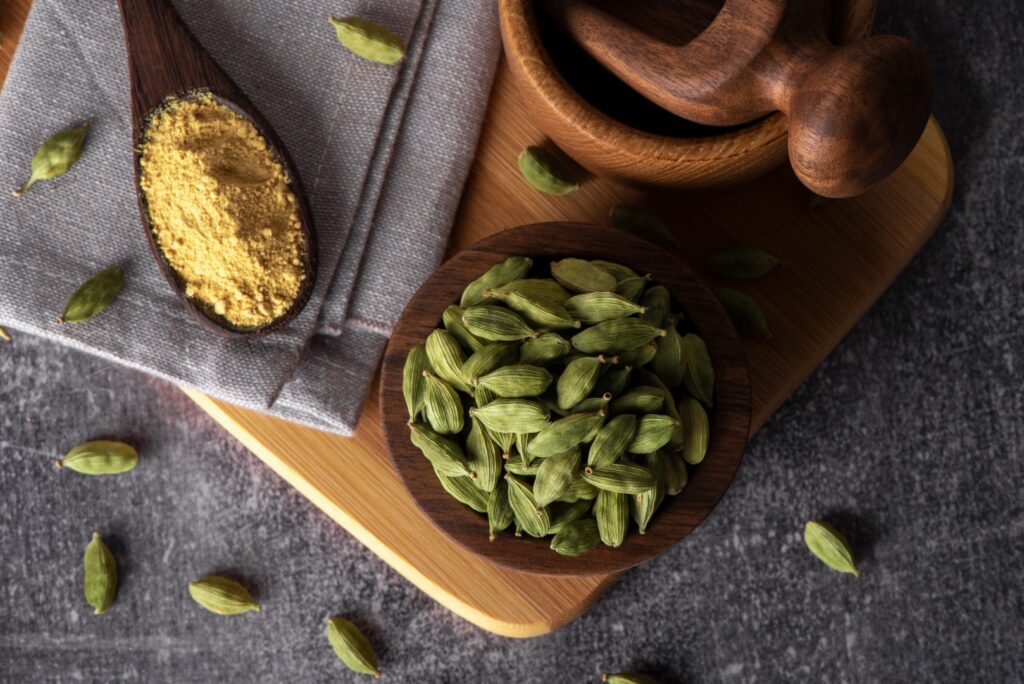 Green cardamom in wooden bowl and spoon. Dry cardamom spice. Image Via Shutterstock