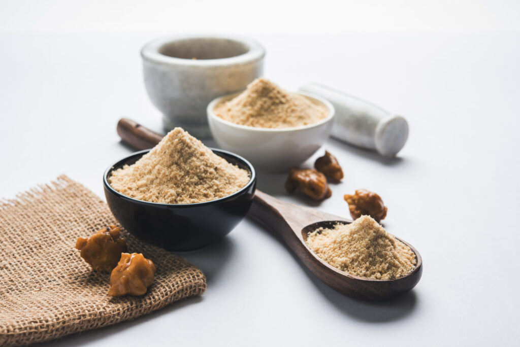 Asafoetida cake and powder or Hing or Heeng which is an important ingredient in Indian food recipes with big wooden spoon. Image Via Shutterstock