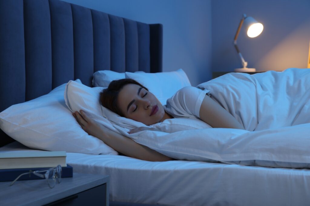 A young woman sleeping in bed at night. Image Via Shutterstock