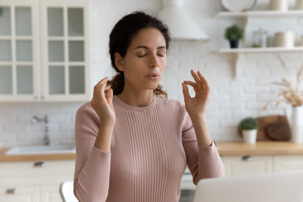 Mindful young woman breathing out with closed eyes. Image Via Shutterstock