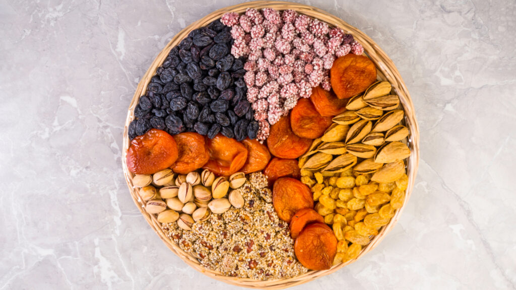 Wooden plate with assorted nuts, apricots, raisins, sesame. Image Via Shutterstock